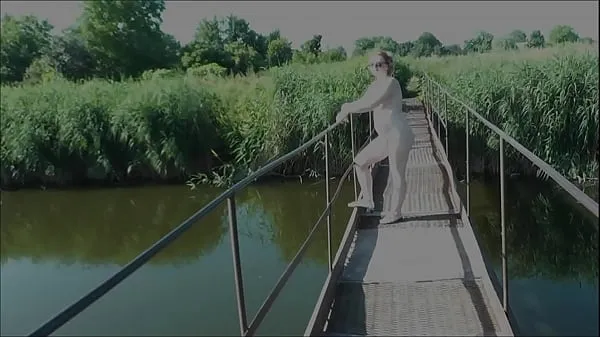 Hiển thị Summer nostalgia. Dressed in sun. Sexy naked woman MILF walks on hanging bridge of river. Nudists. Naturists. Nude beach. Music erotic clip ống điện